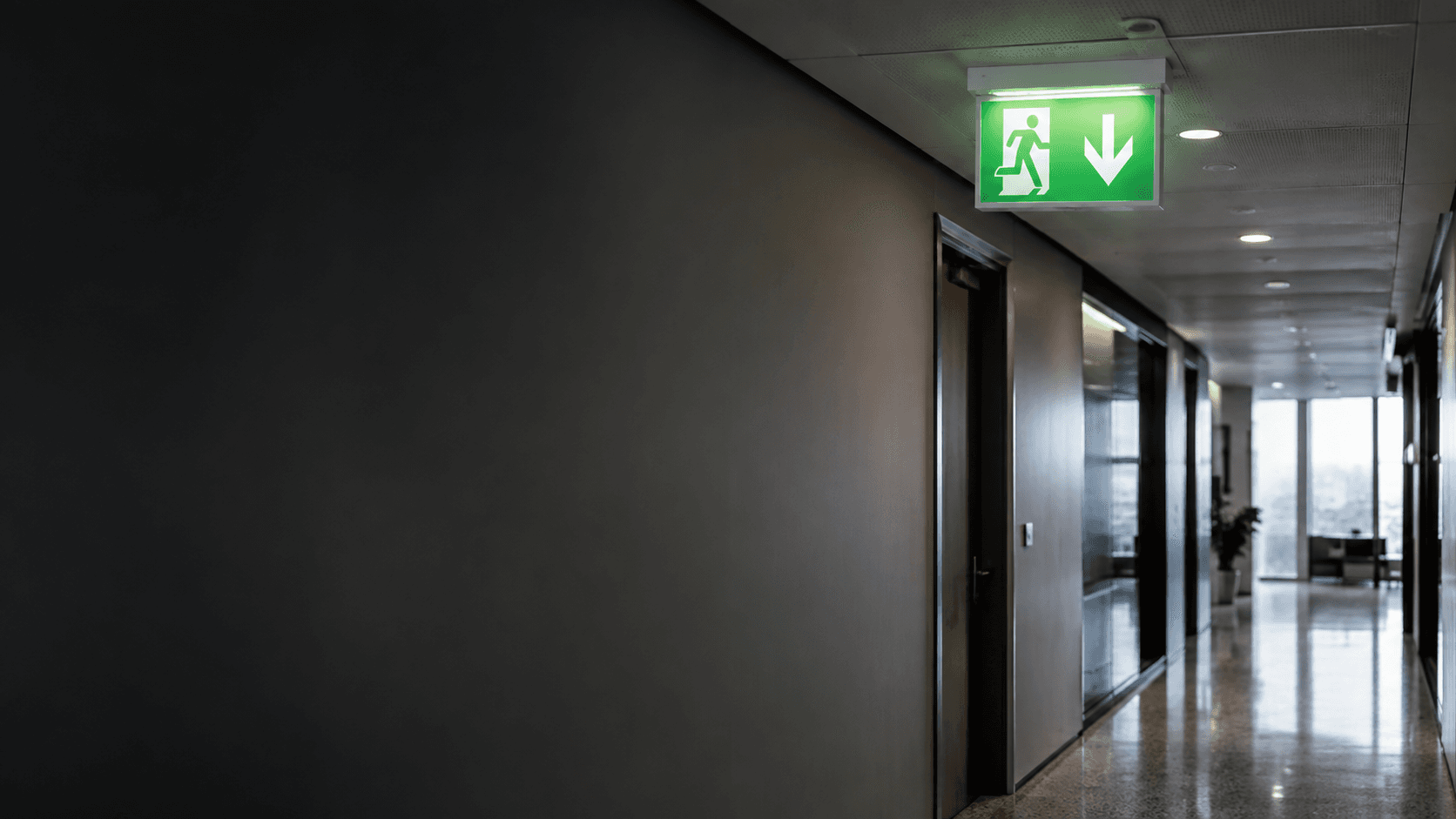 Professional building corridor with illuminated emergency exit guidance and emergency lighting