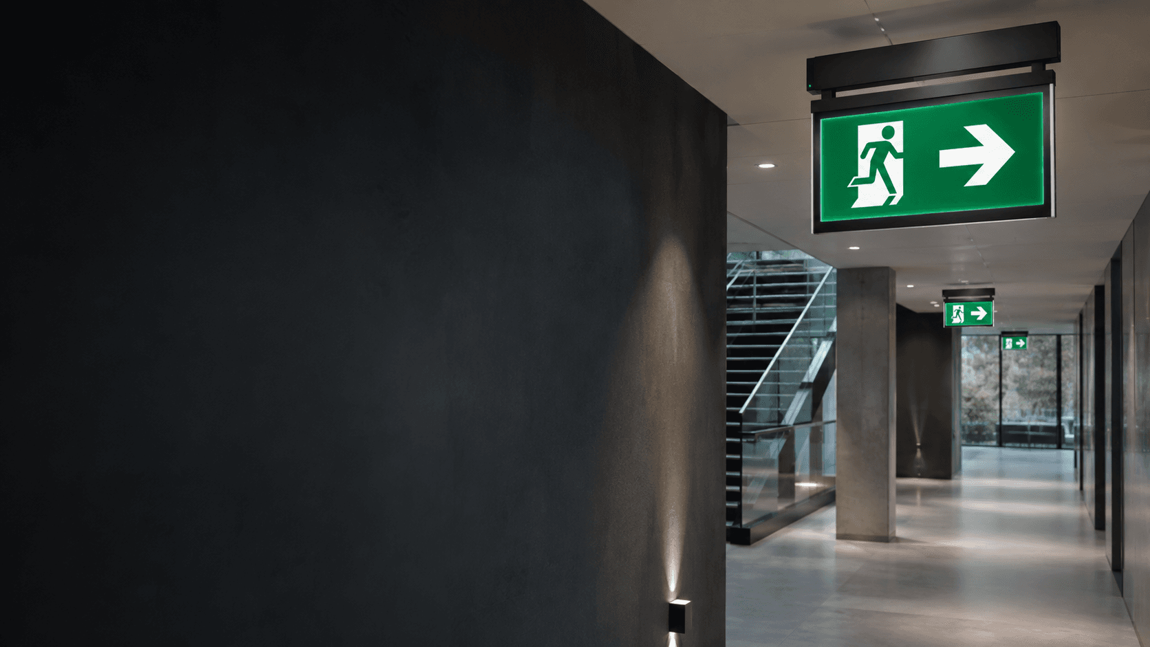 Professional building corridor with illuminated emergency exit guidance and emergency lighting